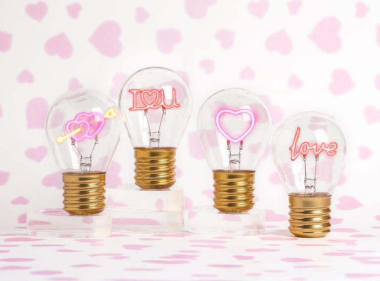 Hearts and arrow neon LED light bulbs displayed on pink decorative background for gifting