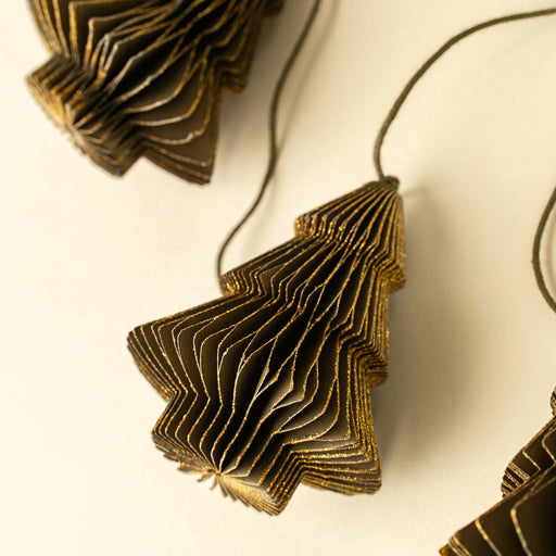 Close-up of a dimensional paper tree showing layered folds and golden-green edges on the garland cord
