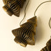 Close-up of a dimensional paper tree showing layered folds and golden-green edges on the garland cord