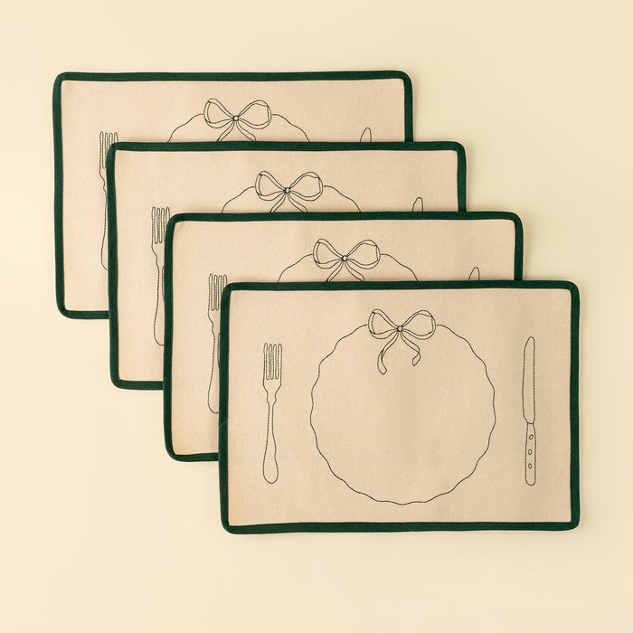 Stacked Bon Appetit placemats tied with a pale ribbon, showing green edging and embroidered place-setting details