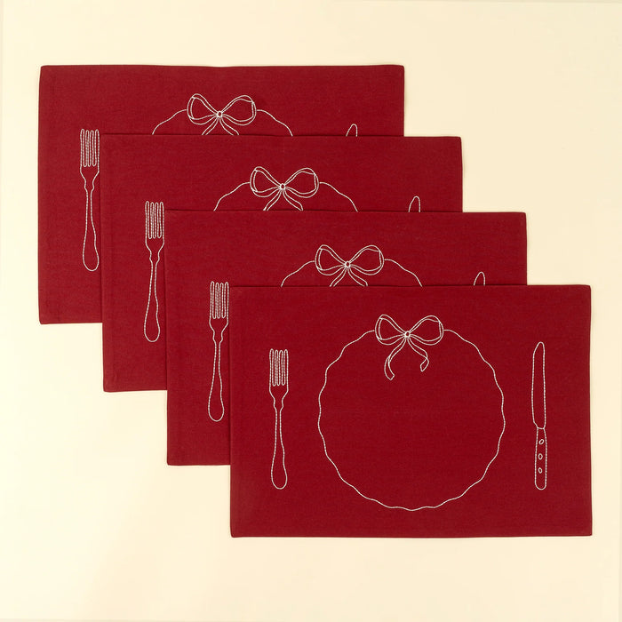 Four matching red Bon Appetit placemats arranged in an overlapping display with white embroidered place-setting designs