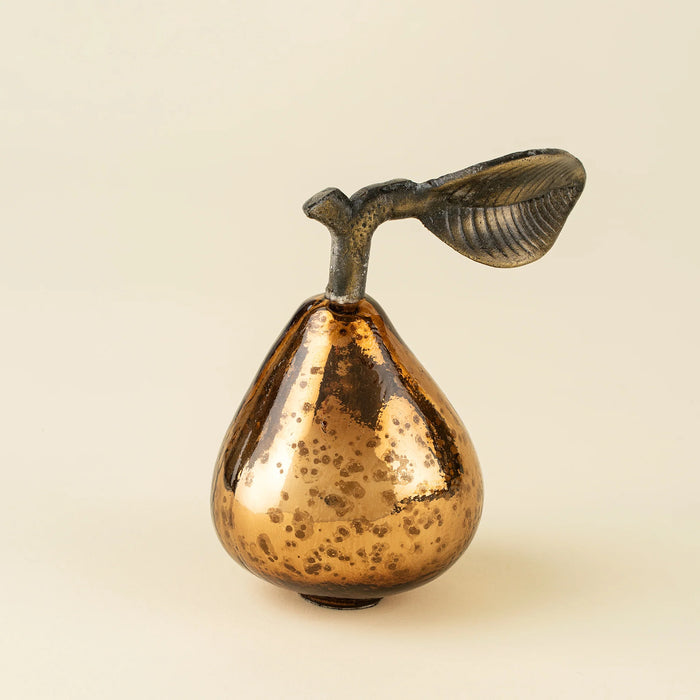 Indaba bronze glass pear with a mottled reflective surface and curved brass leaf on a light background