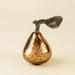 Indaba bronze glass pear with a mottled reflective surface and curved brass leaf on a light background