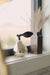 Champagne glass pear on a windowsill beside a tall rectangular vase filled with dried grasses