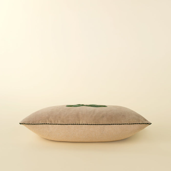Side profile of the filled velvet bow pillow showing its rectangular shape and stitched edge
