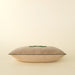 Side profile of the filled velvet bow pillow showing its rectangular shape and stitched edge