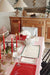 Dining table styled with green-edged placemats, white dinnerware and red candles