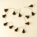 Indaba holiday garland with folded antique green paper trees spaced along a cord on a cream background