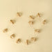 Indaba ivory paper tree garland arranged on a cream background, with folded trees spaced along a pale cord