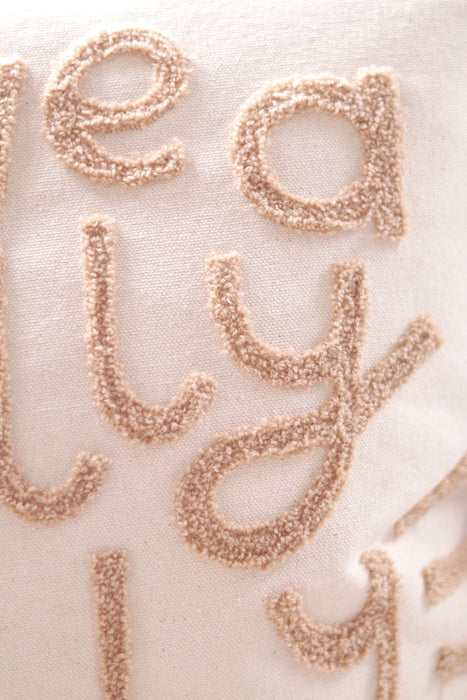 Close-up of plush tan tufted lettering on the Jolly Christmas pillow’s natural cotton fabric