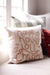 Indaba Jolly Christmas pillow layered with neutral and red cushions on a window seat