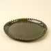 Angled view of a Merida green dinner plate showing its raised edge and decorative hobnail rim