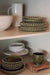 Merida green plates and bowls displayed on shelves alongside neutral dinnerware and a green mug