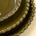 Close-up of stacked Merida plates showing glossy green glaze and rounded hobnail rims