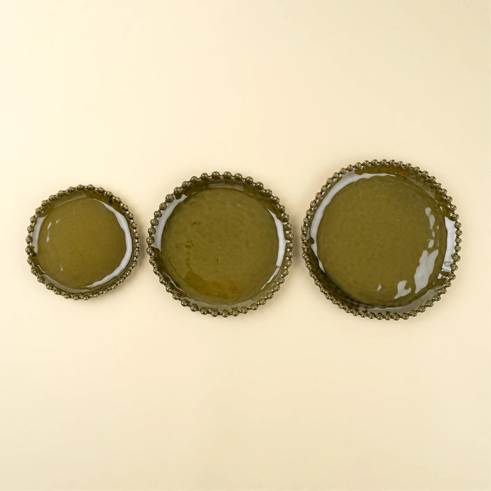 Three Merida green stoneware plates in different sizes arranged side by side