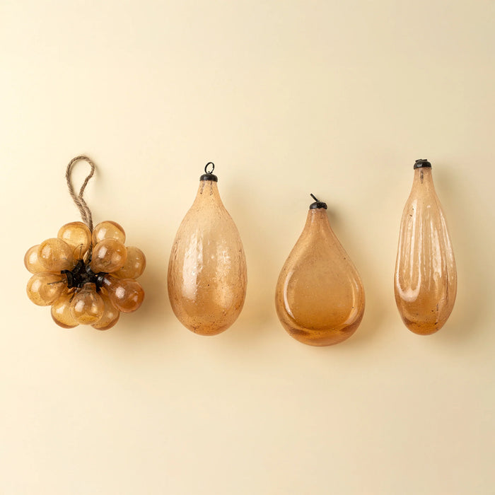 Peach bubble bunch ornament beside three coordinating teardrop-shaped glass ornaments on a cream background