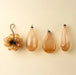 Peach bubble bunch ornament beside three coordinating teardrop-shaped glass ornaments on a cream background