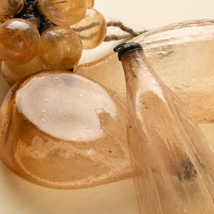 Close-up of peach glass ornaments showing tiny bubbles, warm translucent colour and dark metal caps