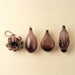 Plum bubble bunch ornament displayed beside three teardrop-shaped glass ornaments on a cream background