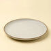 Angled view of an Indaba Rowe ivory stoneware dinner plate with a speckled finish and brown rim