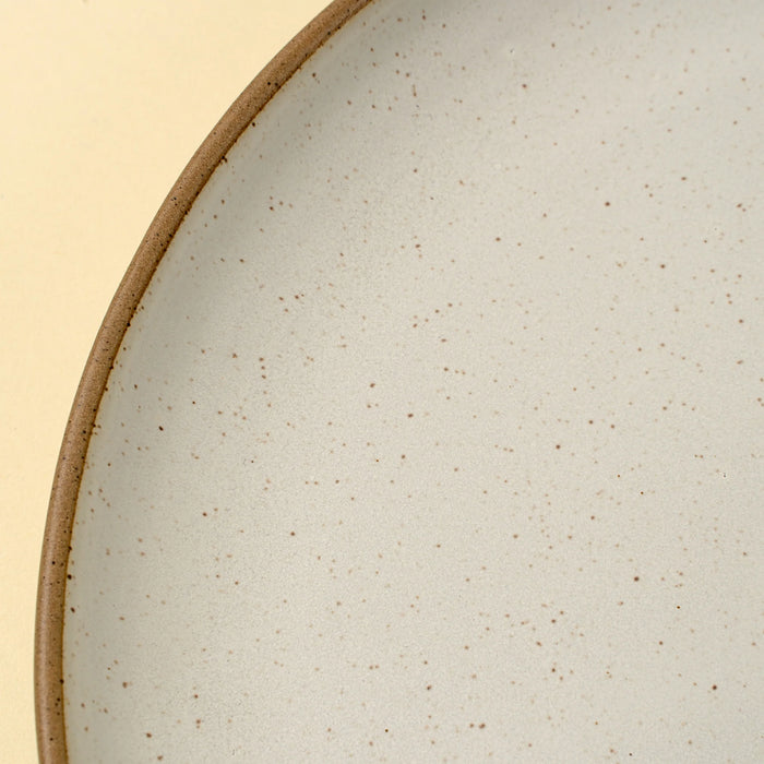 Close-up of the speckled ivory reactive glaze and brown unglazed rim on an Indaba Rowe dinner plate