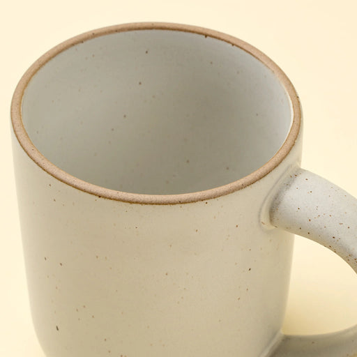 Close-up of an Indaba Rowe ivory mug showing its speckled interior, unglazed rim and curved handle