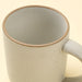 Close-up of an Indaba Rowe ivory mug showing its speckled interior, unglazed rim and curved handle