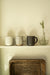 Ivory stoneware mug displayed beside striped and dark mugs and a glass vase on a shelf