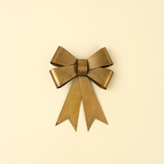Small iron bow ornament with a rustic brass finish, layered ribbon loops and two long notched tails.
