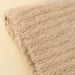 Close-up of the oat Snug Throw showing its textured knit surface and finished edge