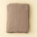 Folded Indaba Snug Throw in Tuffet, showing its warm taupe colour and fluffy knit texture