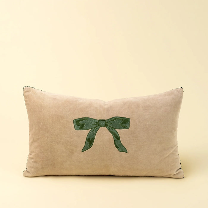 Front view of Indaba’s rectangular neutral velvet pillow with a centred green embroidered bow