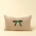 Front view of Indaba’s rectangular neutral velvet pillow with a centred green embroidered bow