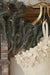 Close-up of the stocking’s felt hanging loop and layered cream flowers beside evergreen branches