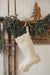 Indaba floral felt stocking hanging from a wooden mantel decorated with evergreen garland